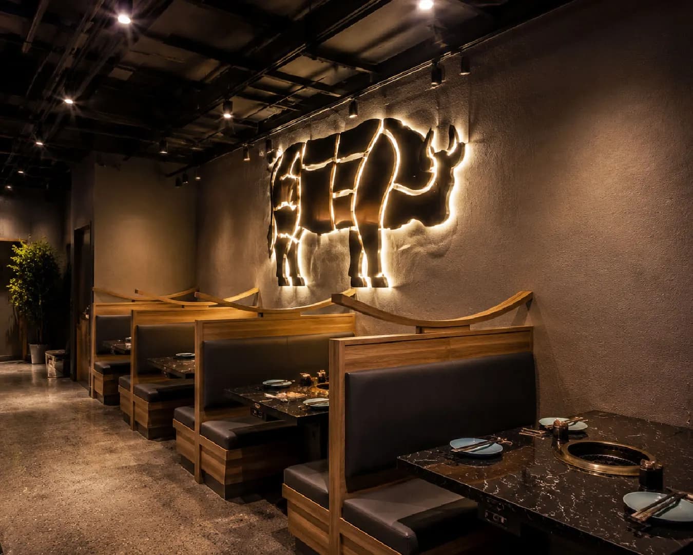The Gyumono dining room in Pickering, with booth seating and a lit bull emblem on the wall